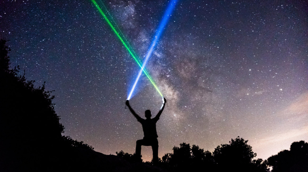 man-wielding-blue-and-green-lightsabers-in-the-starry-night-sky.jpg