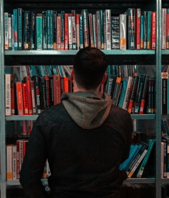 Άνδρας όρθιος μπροστά από βιβλιοθήκη γεμάτη βιβλία