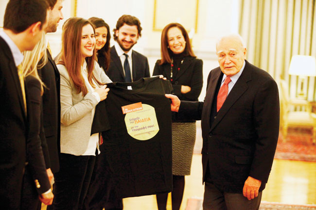  Ο τ. ΠτΔ Κάρολος Παπούλιας υπογράφει την δράση του ΔΙΚΤΥΟΥ «Invest In Education» και λαμβάνει δώρο αναμνηστικό μπλουζάκι από ομάδα νέων του ΔΙΚΤΥΟΥ