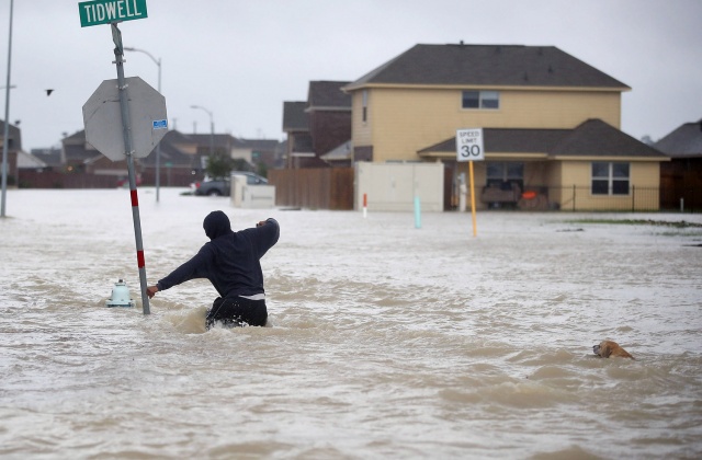 Ένας άνθρωπος περπατάει στον πλημμυρισμένο δρόμο με τον σκύλο του