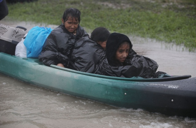 Παιδιά μεταφέρονται με βάρκα καθώς εκκενώνουν τα σπίτια τους αφού η περιοχή πλημμύρισε από τον τυφώνα Harvey στις 28 Αυγούστου 2017 στο Χιούστον