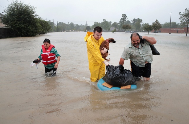 Άνθρωποι περπατάνε στον πλημμυρισμένο δρόμο αφού έχουν εγκαταλείψει το σπίτι τους