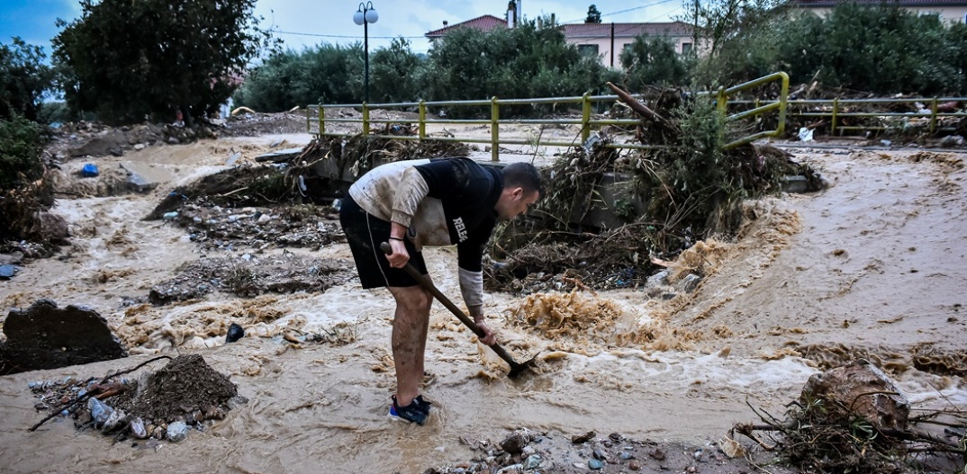Κάτοικος του Βόλου επιχειρεί να βγάλει τη λάσπη από σημείο της πόλης