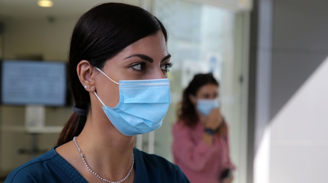 Γυναίκα φορά μάσκα προστασίας από τον κορωνοϊό σε εσωτερικό χώρο