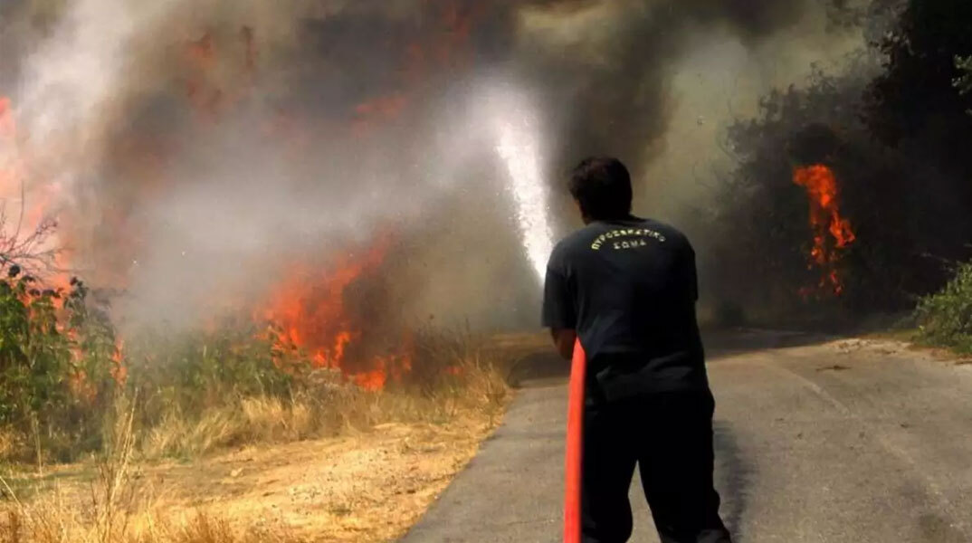 Πυροσβέστης ρίχνει νερό σε δασική πυρκαγιά