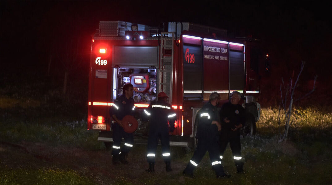 Πυροσβέστες τη νύχτα μπροστά από πυροσβεστικό όχημα