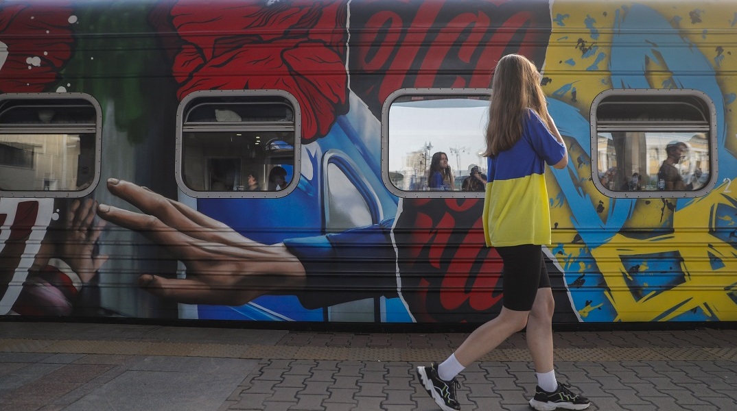 Κοπέλα με την ουκρανική σημαία περνά μπροστά από τρένο στο Κίεβο