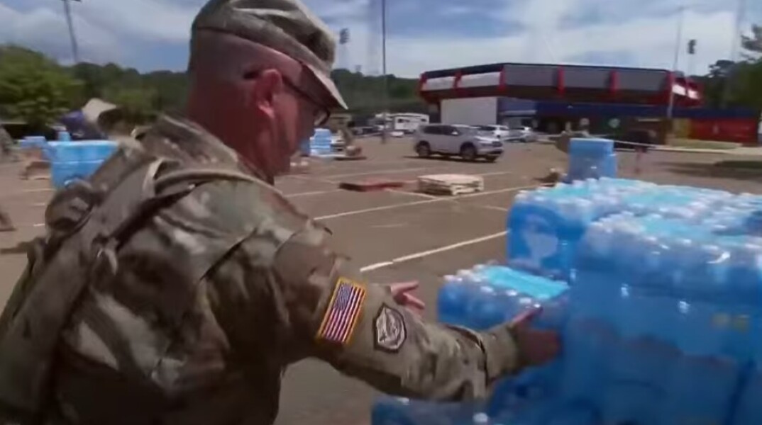 Στρατιώτης μεταφέρει μπουκάλια με νερό στο Τζάκσον