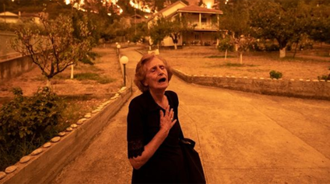 Ηλικιωμένη σε απόγνωση, καθώς εγκαταλείπει το σπίτι της που τυλίγεται στις φλόγες, στο χωριό Γούβες, στη βόρεια Εύβοια
