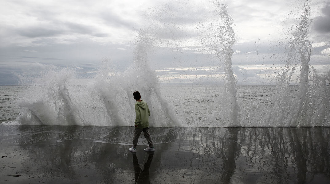Παιδί παίζει με τα κύματα στο Παλαιό Φάληρο, καθώς η κακοκαιρία EVA επηρεάζει την Αττική