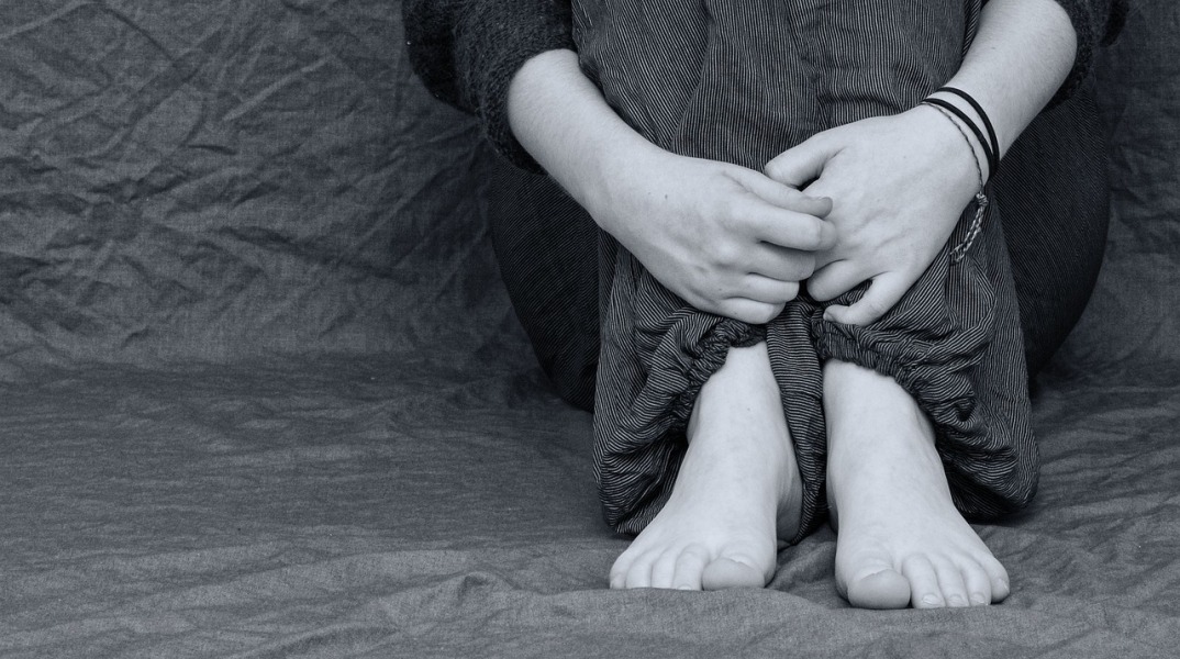 Παιδί με μαζεμένα τα πόδια κοντά στο κορμί του σε ασπρόμαυρη εικόνα που παραπέμπει σε bullying
