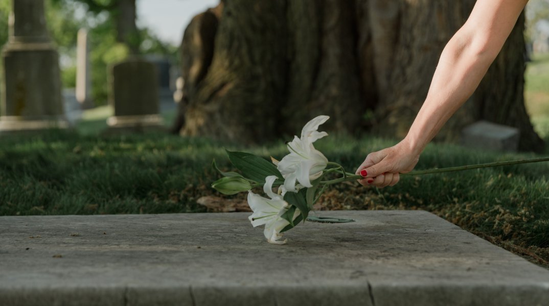 Χέρι που επαναποθέτει λουλούδια σε τάφο
