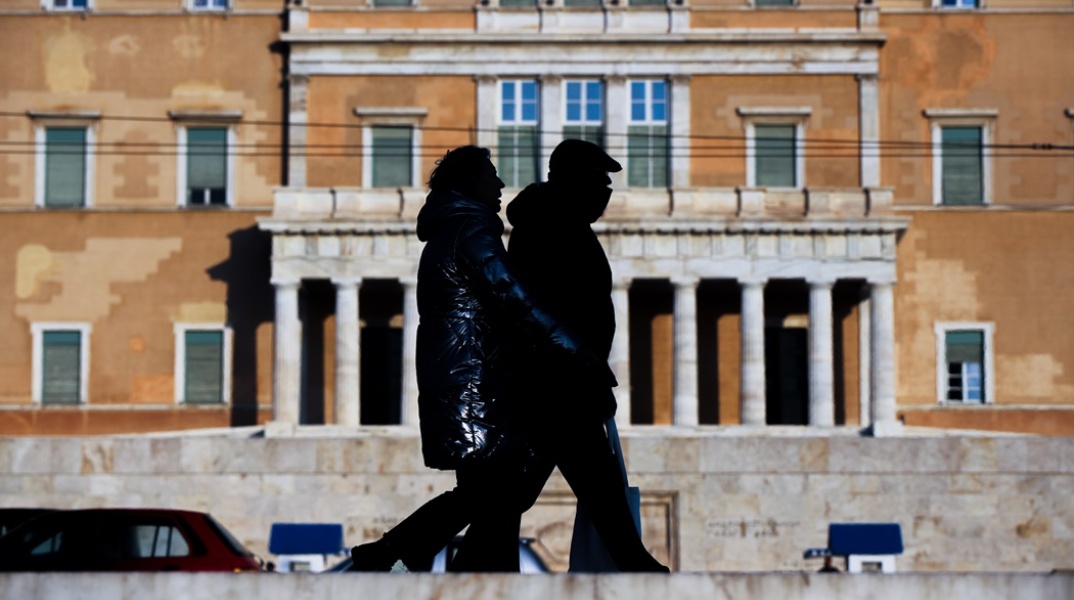 Πολίτες με μάσκες προστασίας από τον κορωνοϊό μπροστά από τη Βουλή των Ελλήνων