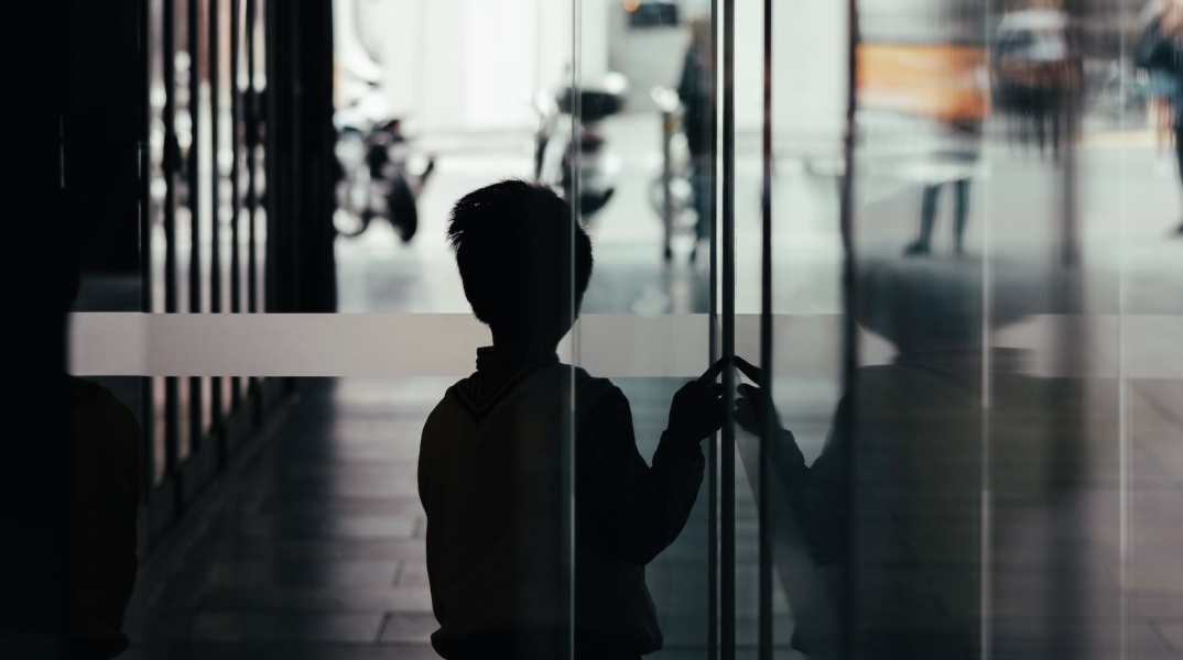 Παιδί σε σκοτεινό διάδρομο φαίνεται να φοβάται να βγει στο φως - Εικόνα που παραπέμπει σε κακοποίηση και bullying