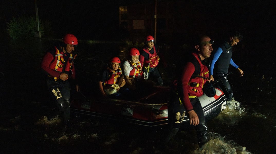 Ομάδα διασωστών κουβαλάει με τη βάρκα ζευγάρι ηλικιωμένων