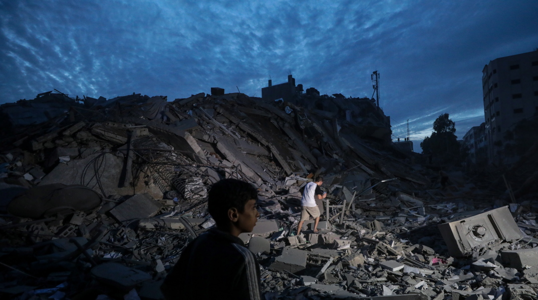 Παιδί περνάει μπροστά από κατεστραμμένο κτίριο στη Γάζα