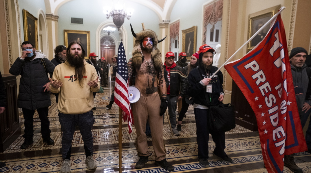 Στιγμιότυπο από την εισβολή στο Καπιτώλιο, με τον QAnon shaman στο επίκεντρο