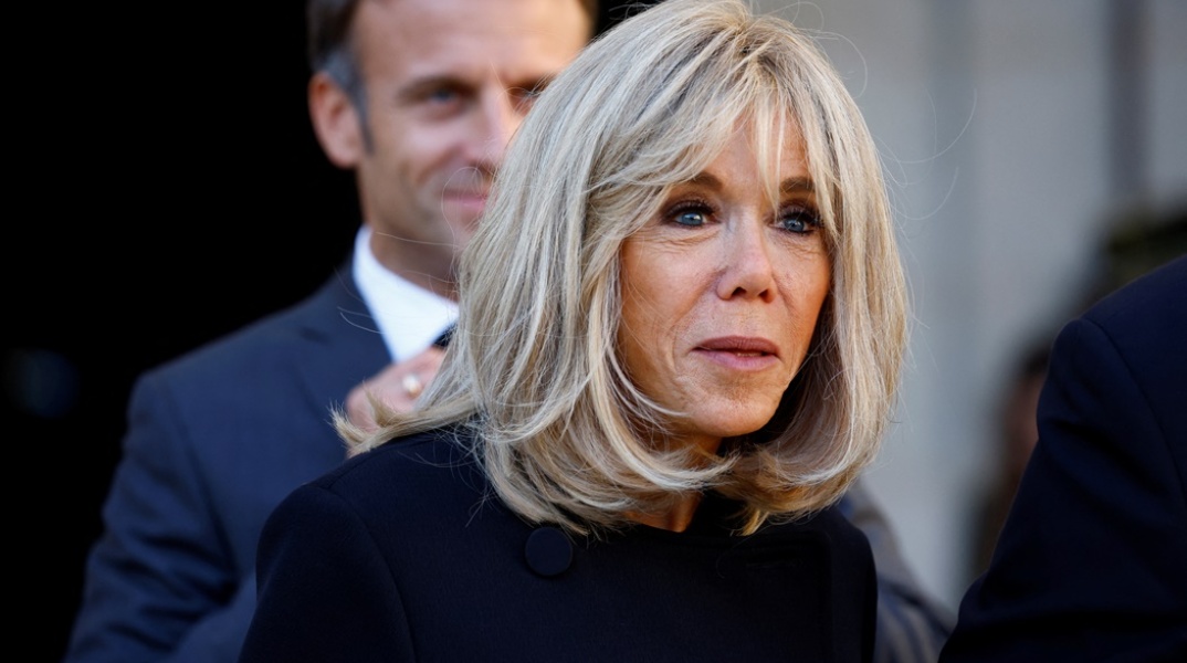 Η Μπριζίτ Μακρόν και πίσω της ο Εμανουέλ Μακρόν