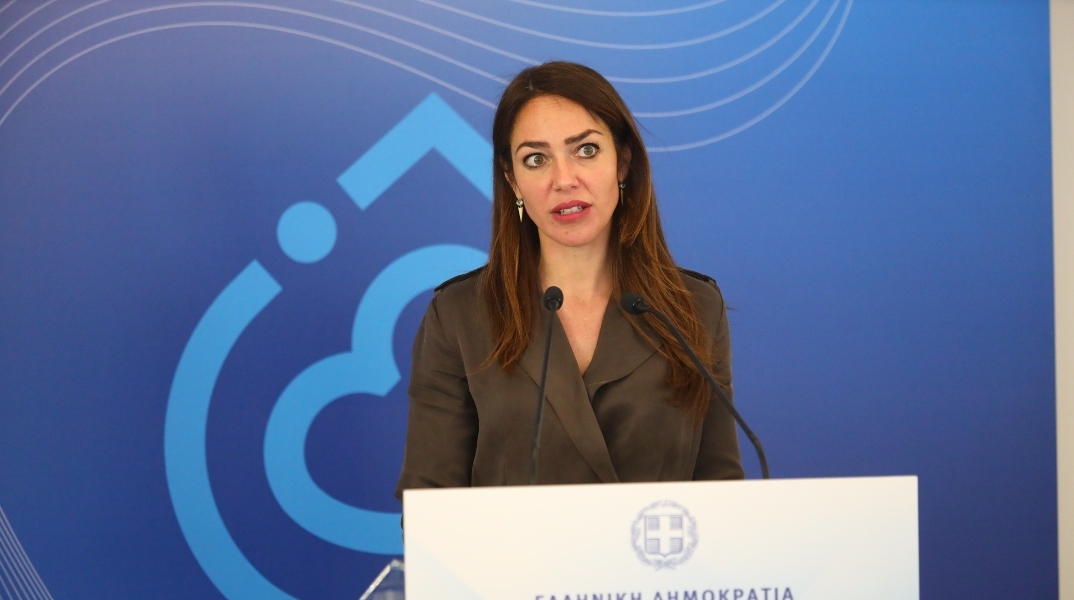 H υπουργός Εργασίας, Δόμνα Μιχαηλίδου μιλάει όρθια στο βήμα σε συνέντευξη τύπου
