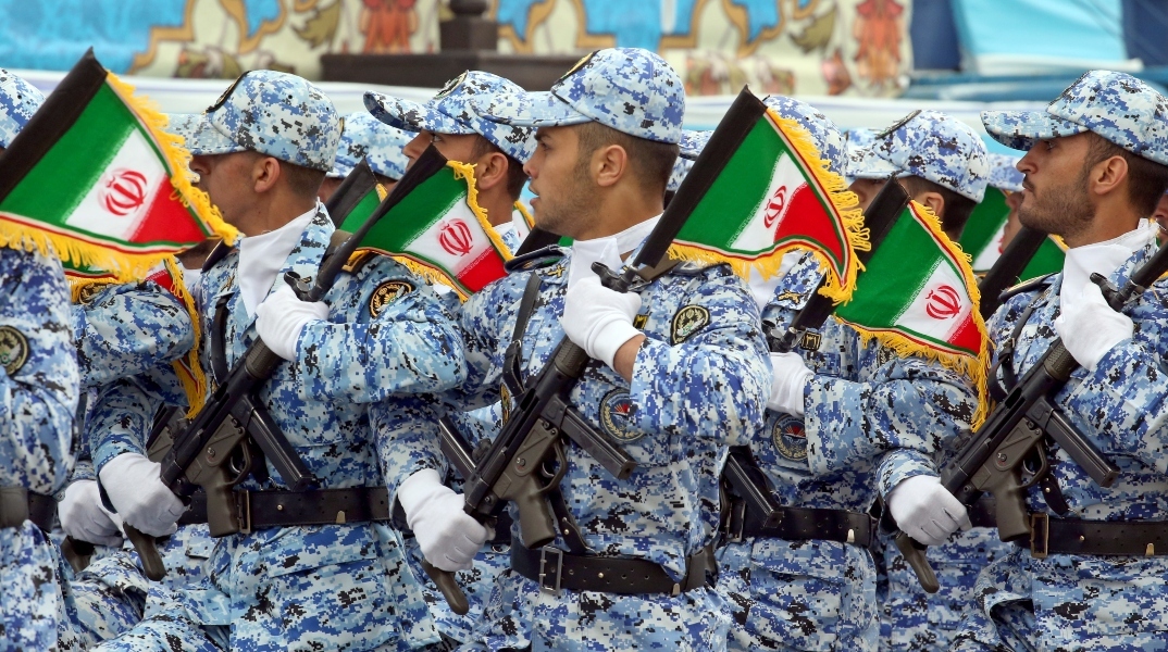 Μέλη της Πολεμικής Αεροπορίας της Ισλαμικής Δημοκρατίας του Ιράν παρελαύνουν κρατώντας όπλα και ιρανικές σημαίες