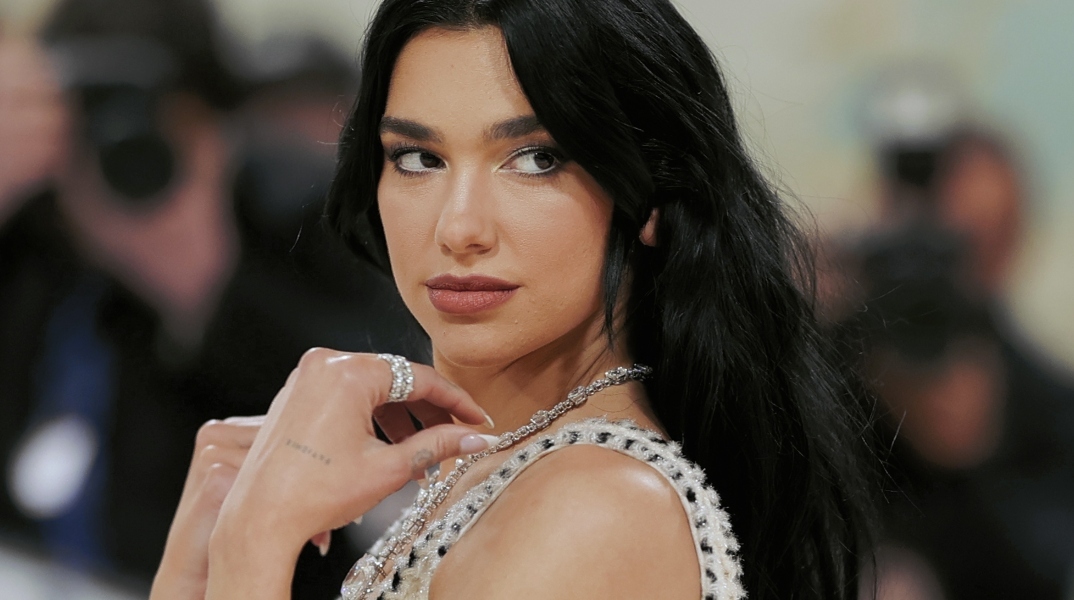 Η Dua Lipa σε κοντινό πλάνο φορώντας άσπρο φόρεμα και κοσμήματα