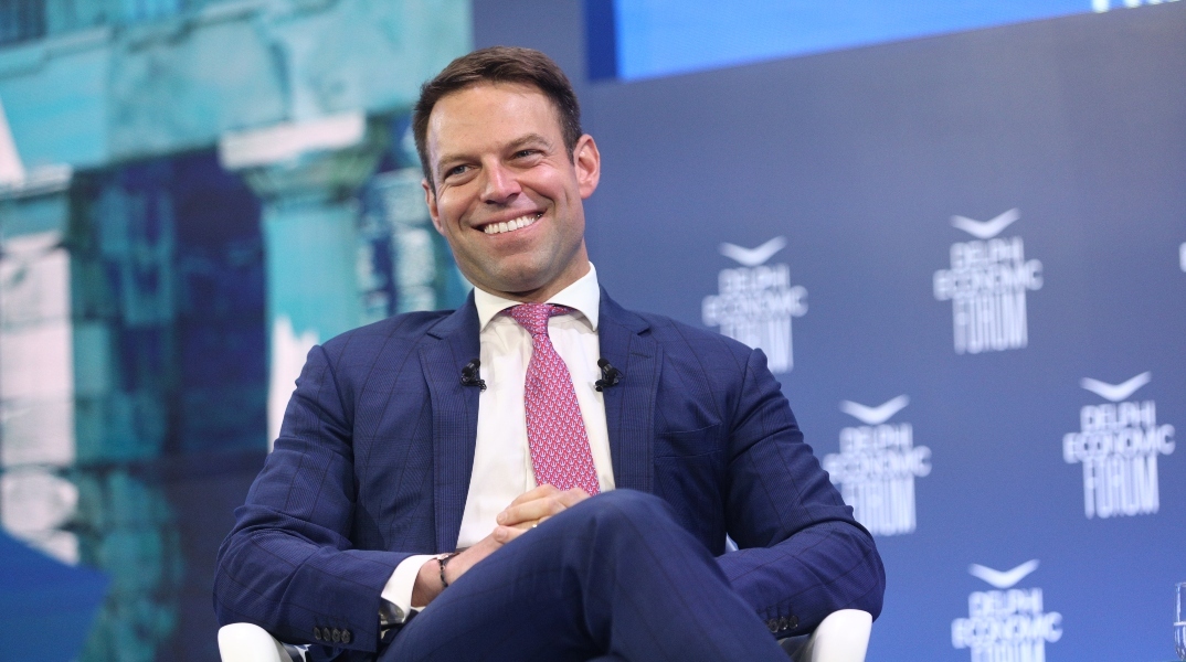 Ο Στέφανος Κασσελάκης χαμογελαστός κάθεται σταυροπόδι στο 9ο Φόρουμ των Δελφών για συνέντευξη