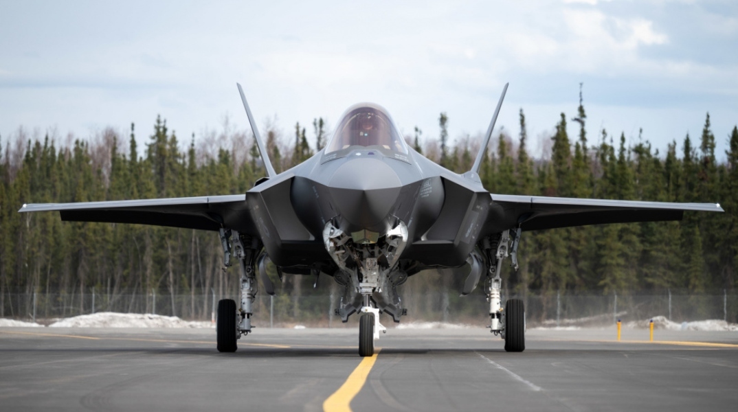 F-35 γκρι σε κοντινό μπροστινό πλάνο, προσγειωμένο. Από πίσω υπάρχουν δέντρα