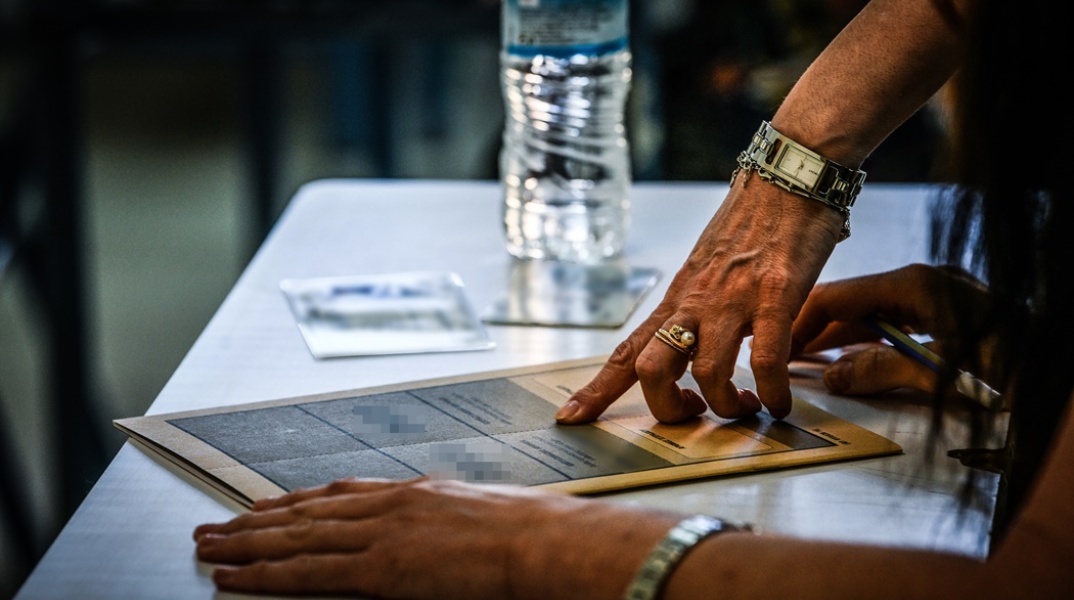 Τετράδιο πανελληνίων εξετάσεων και χέρι που κάτι δείχνει στον ή στην εξεταζόμενη