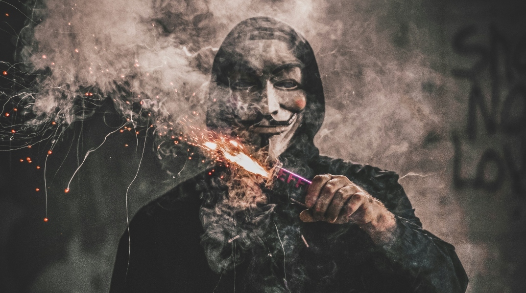 Άνδρας φορώντας μάσκα κρατάει φλεγόμενο πυρσό