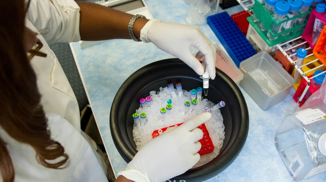 Ιατρός κρατάει μπουκαλάκια με δείγματα πάνω από ένα δοχεία με πάγο