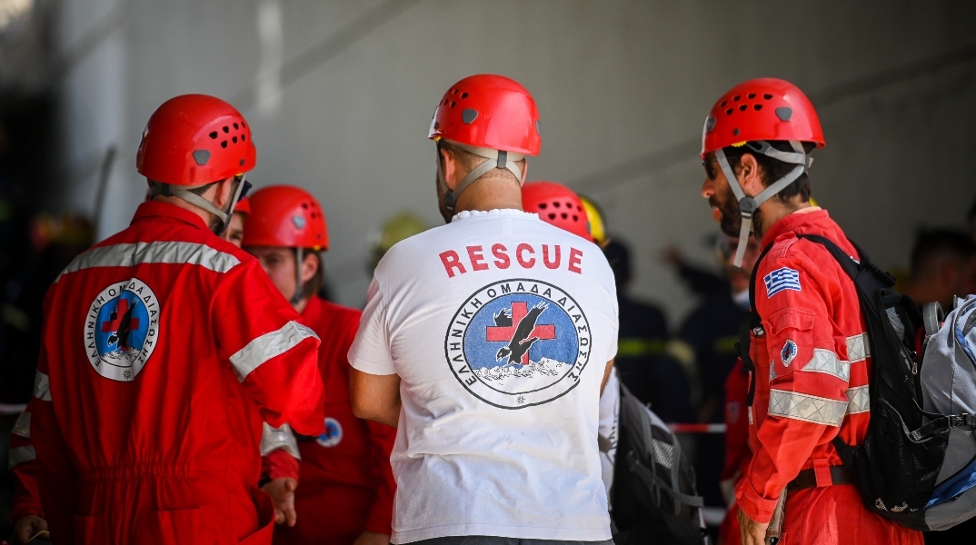 Διασώστες φορώντας κόκκινες στολές και άσπρη μπλούζα με κράνη και σακίδιο