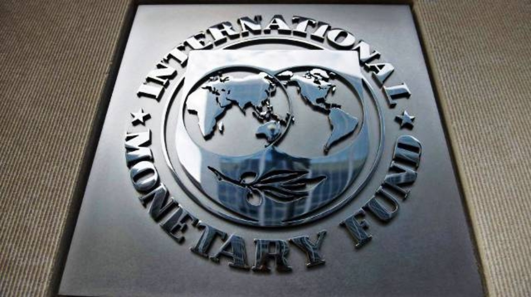 Μεταλλικό στρογγυλό σύμβολο του ΔΝΤ με τον παγκόσμιο χάρτη και ένα κλαδί ελιάς