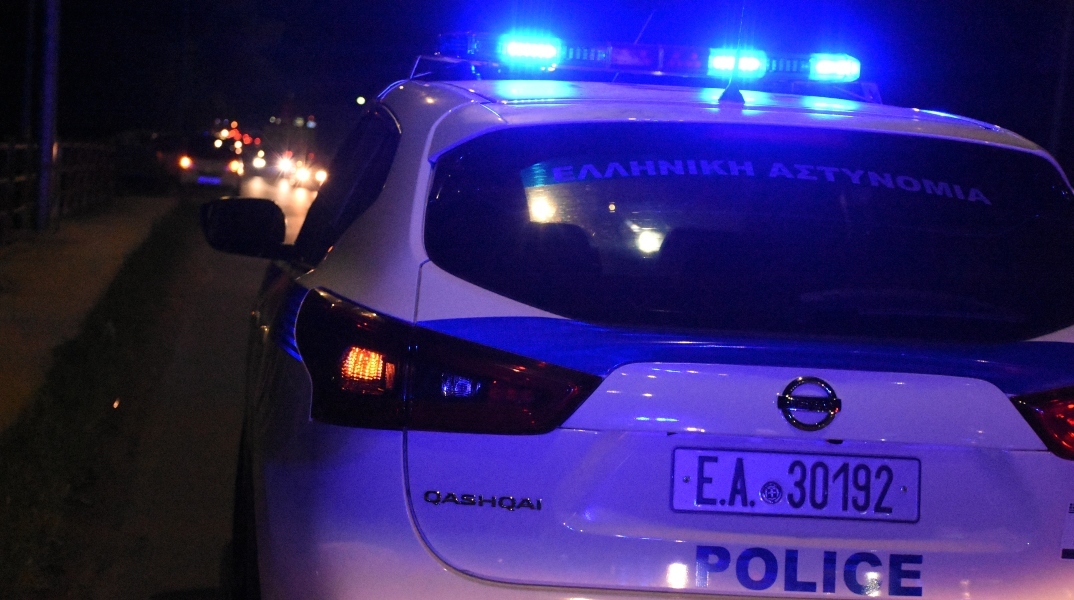 Λευκό περιπολικό τη νύχτα με μπλε φάρους