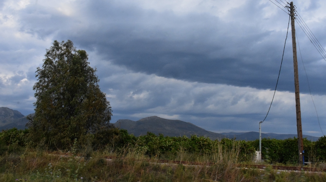 Βουνά, σύννεφα, δέντρα και στύλος της ΔΕΗ