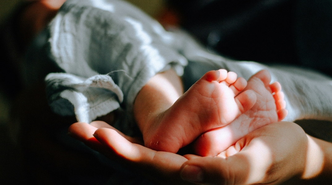 Ένα χέρι κρατάει δύο πόδια μωρού