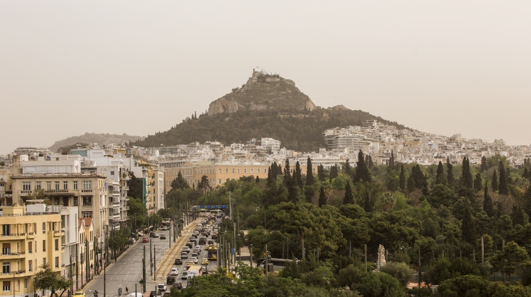 Λόφος με δέντρα - πολυκατοικίες και αυτοκίνητα