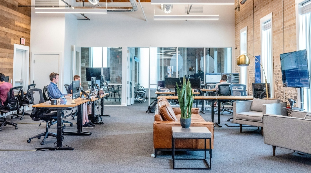 Αίθουσα με τραπέζια, καρέκλες, γραφεία, εργαζόμενους, γλάστρα