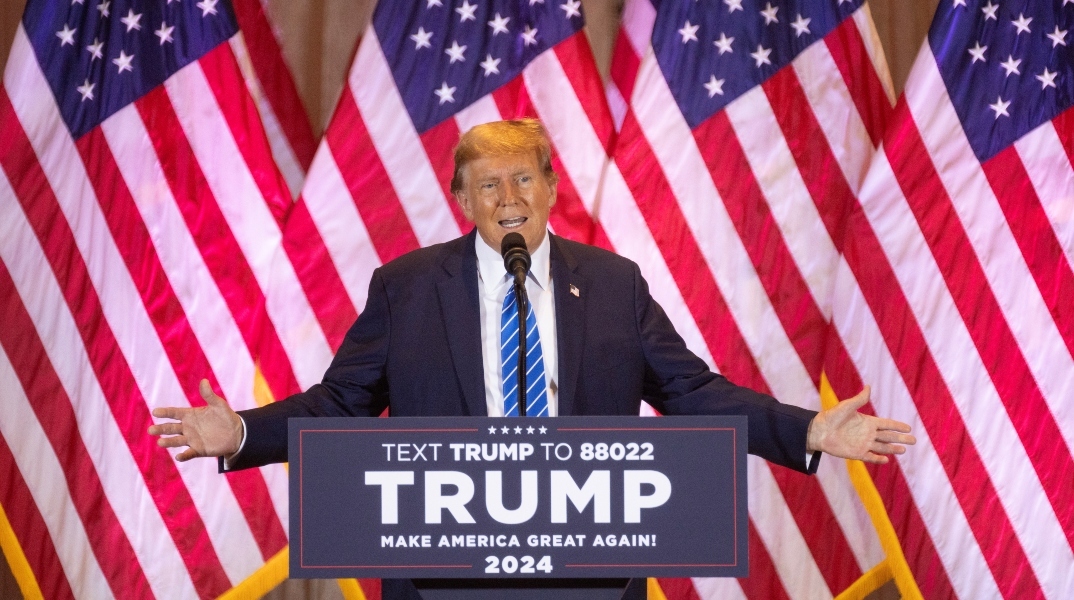 Ο Ντόναλντ Τραμπ, μιλάει όρθιος στο βάθρο - αμερικανικές σημαίες