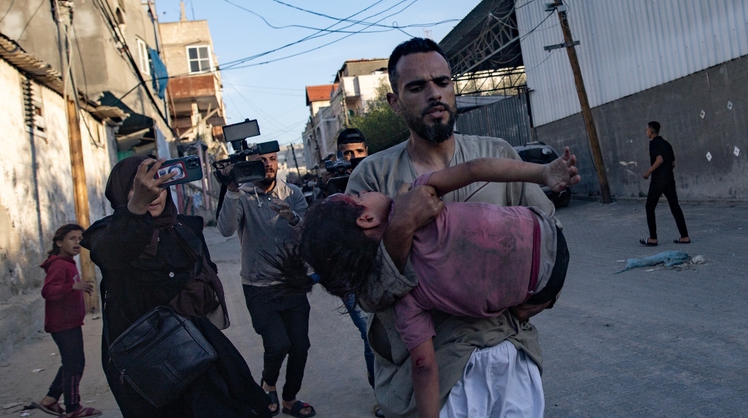 ανδρας κραταει τραυματισμένο παιδι