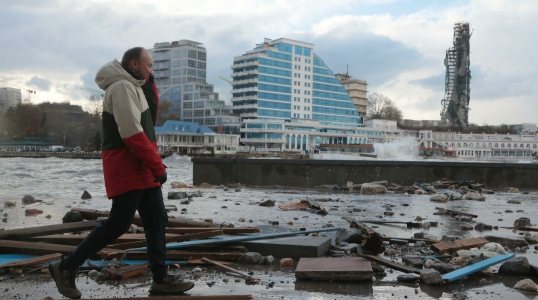 ανδρας περπαταει μπροστα απο κατεστραμμενα κτηρια