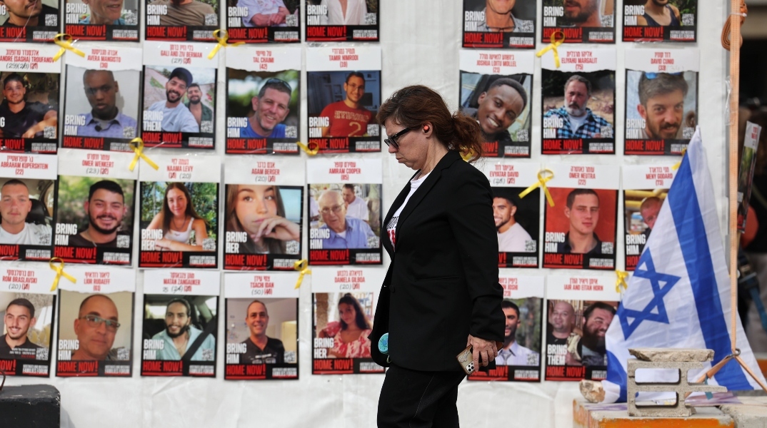 γυναικα περπαταει μπροστα απο τα προτραιτα ομηρων της Χαμάς