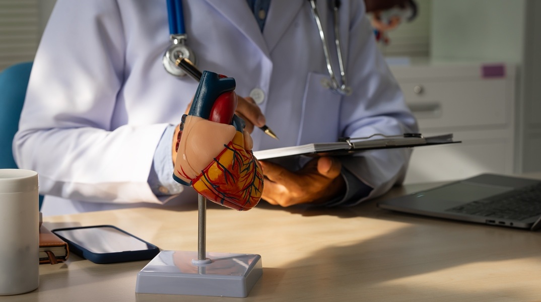 Γιατρός που σημειώνει έχοντας στο γραφείο του ένα ομοίωμα καρδιάς