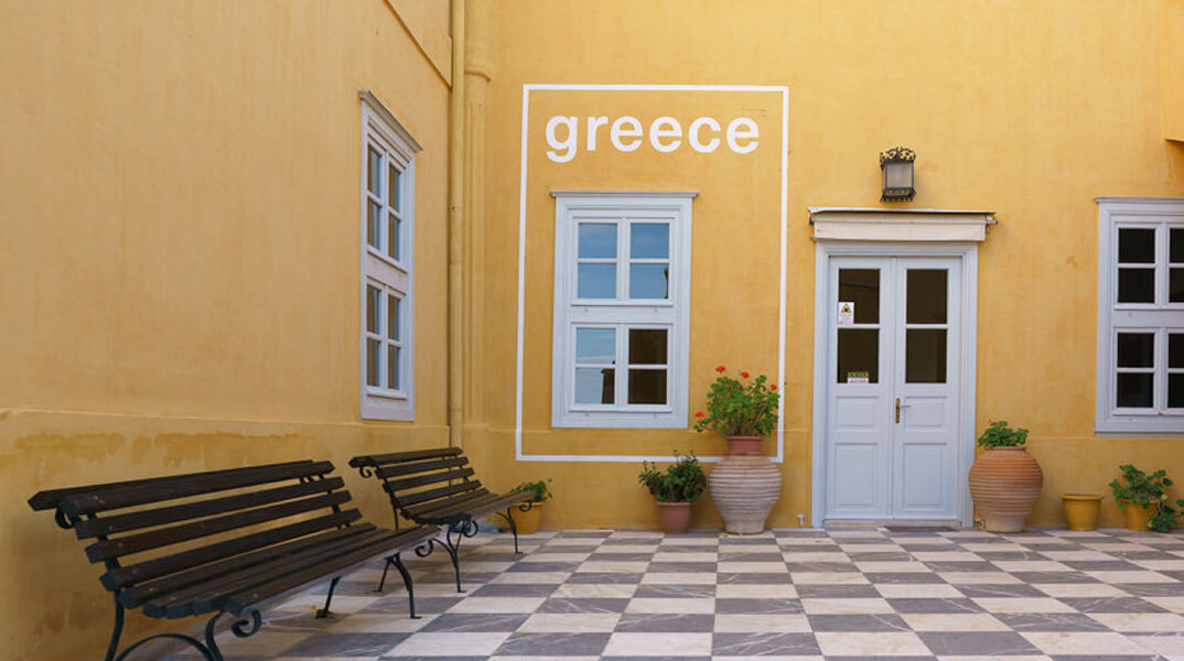 Άποψη της κεντρικής αυλής της Ιστορικής Οικίας Λαζάρου Κουντουριώτη με την τοιχογραφία που μετατρέπει παράθυρο της κεντρικής αυλής της Ιστορικής Οικίας Λαζάρου Κουντουριώτη σε τουριστική αφίσα