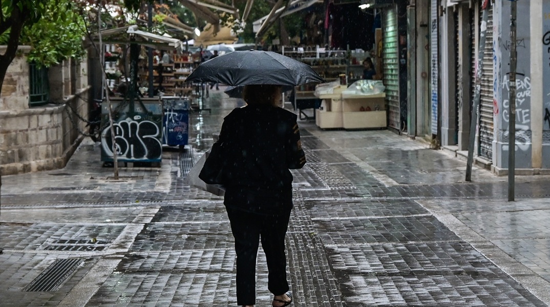 Άτομο με ομπρέλα περπατά εν μέσω βροχής