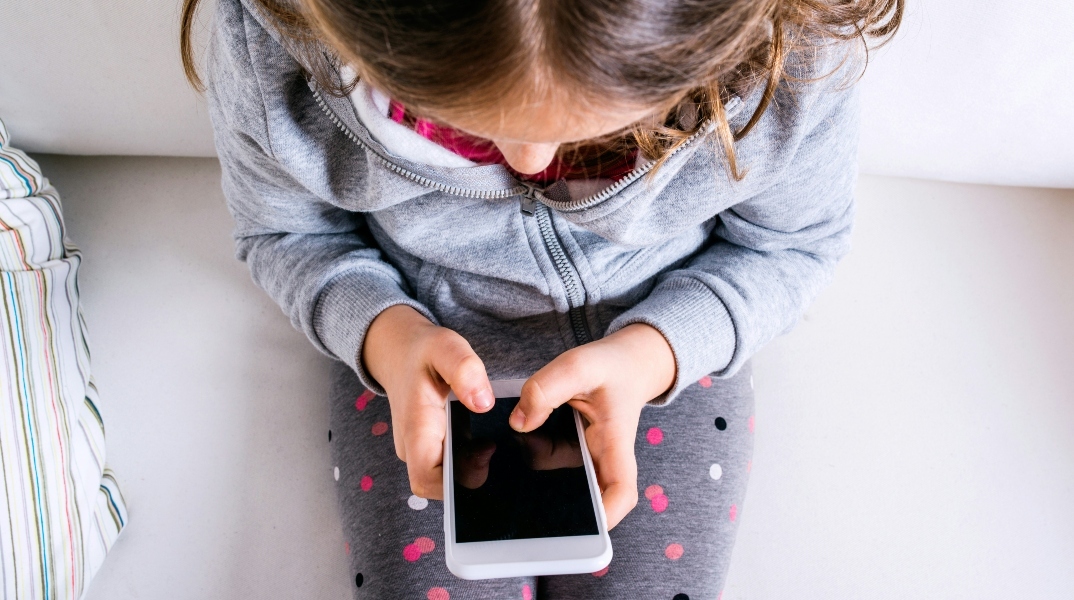 παιδι καθισμενο κραταει κινητο