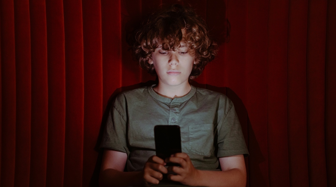 παιδι καθισμενο κραταει κινητο