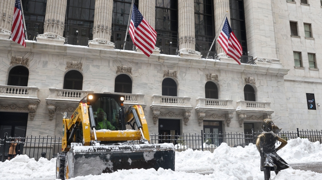 Εργάτες καθαρίζουν το χιόνι μπροστά στο γλυπτό «Το Ατρόμητο Κορίτσι» έξω από το Χρηματιστήριο της Νέας Υόρκης 