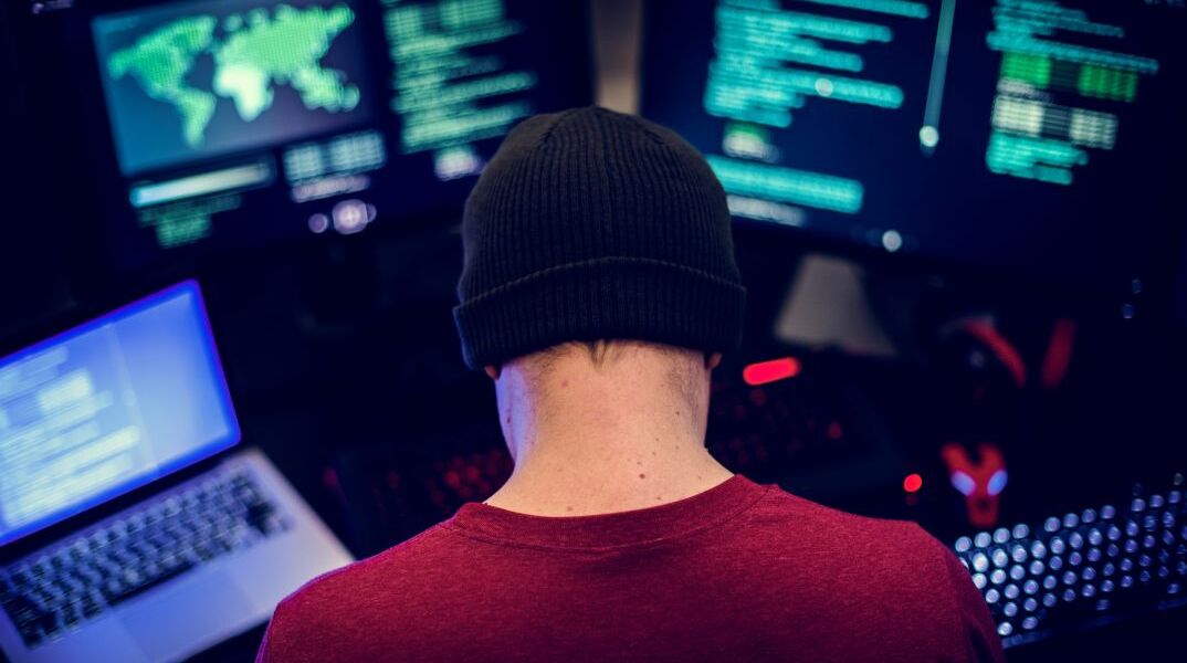 Χάκερ μπροστά από οθόνες υπολογιστών