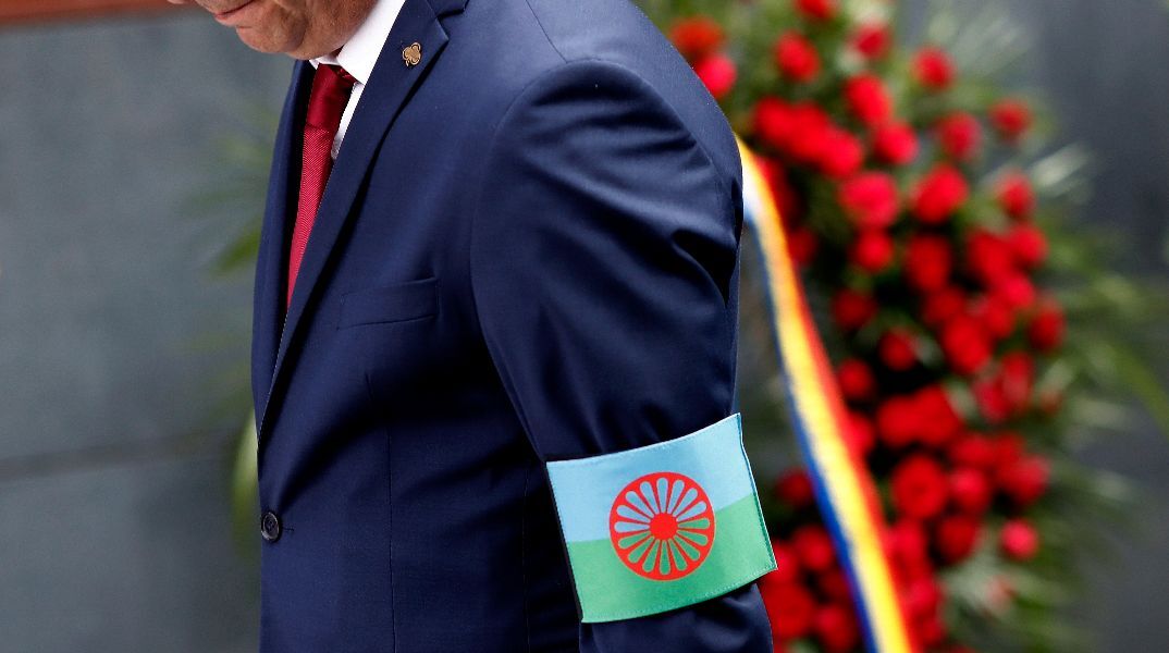 Άνδρας με τη σημαία των Ρομά ως περιβραχιόνιο, αποτίει φόρο τιμής στη τελετή μνήμης του Ολοκαυτώματος των Ρομά, στη Ρουμανία