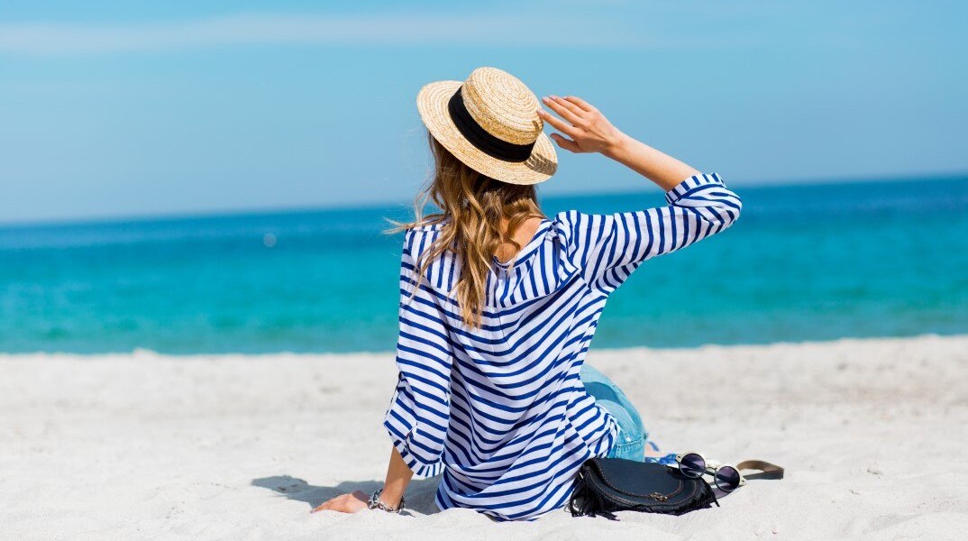 Γυναίκα με ψάθινο καπέλο στην παραλία